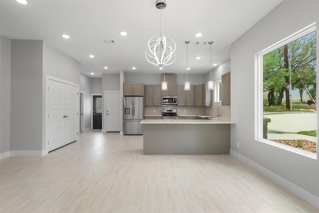 301 Knights Row, Horseshoe Bay, TX 78657 - kitchen with appliances with stainless steel finishes, a chandelier, light countertops, backsplash, and a peninsula