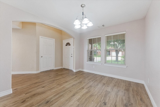 16546 Whitaker Creek Dr, Houston, TX 77095 - spare room featuring arched walkways, light wood-type flooring, and a chandelier