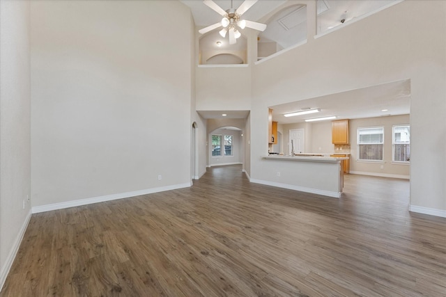 16546 Whitaker Creek Dr, Houston, TX 77095 - unfurnished living room featuring ceiling fan, plenty of natural light, wood finished floors, arched walkways, and a towering ceiling