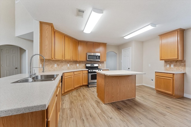 16546 Whitaker Creek Dr, Houston, TX 77095 - kitchen featuring appliances with stainless steel finishes, arched walkways, light wood-style flooring, and tasteful backsplash