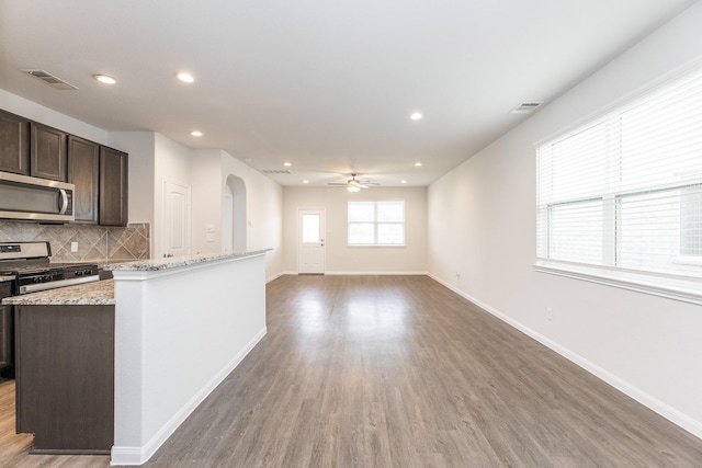 2931 Orchid Ranch Dr, Katy, TX 77494 - kitchen with appliances with stainless steel finishes, arched walkways, dark brown cabinetry, ceiling fan, and light wood-style flooring