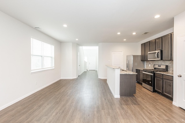 2931 Orchid Ranch Dr, Katy, TX 77494 - kitchen featuring stainless steel appliances, light wood-style flooring, dark brown cabinetry, backsplash, and recessed lighting