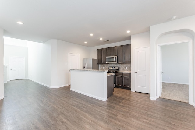 2931 Orchid Ranch Dr, Katy, TX 77494 - kitchen featuring appliances with stainless steel finishes, dark brown cabinetry, recessed lighting, wood finished floors, and tasteful backsplash