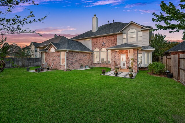 2331 Fern Bend Ln, Katy, TX 77494 - back of property at dusk with a patio area, a chimney, brick siding, a fenced backyard, and roof with shingles