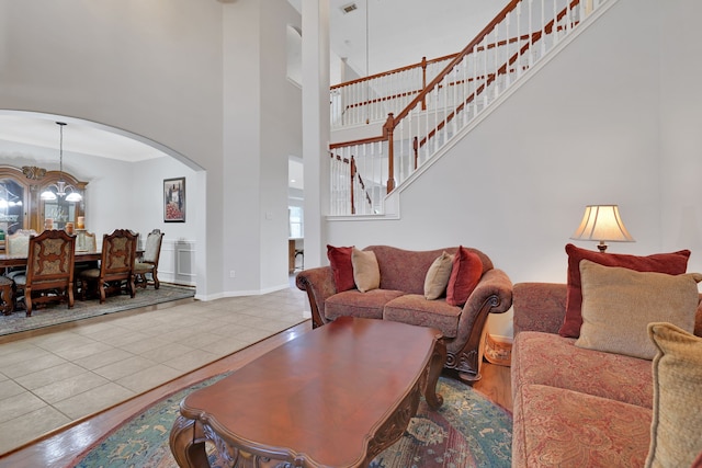 2331 Fern Bend Ln, Katy, TX 77494 - living room with a chandelier, stairs, arched walkways, tile patterned floors, and a high ceiling