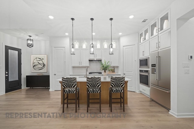 2722 Woodforest Pkwy N, Montgomery, TX 77316 - kitchen featuring appliances with stainless steel finishes, a breakfast bar, light countertops, white cabinetry, and recessed lighting