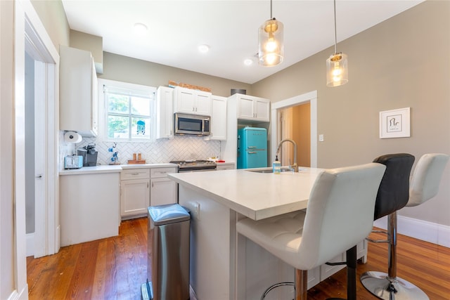 912 Sealy St, Galveston, TX 77550 - kitchen with appliances with stainless steel finishes, a kitchen breakfast bar, tasteful backsplash, white cabinets, and dark wood-style flooring