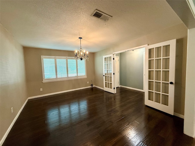 1502 Robin St, Mineola, TX 75773 - empty room featuring french doors, a textured ceiling, a chandelier, and dark wood finished floors