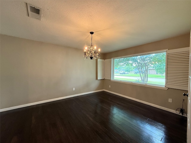 1502 Robin St, Mineola, TX 75773 - spare room featuring dark wood-type flooring, a chandelier, and a textured ceiling