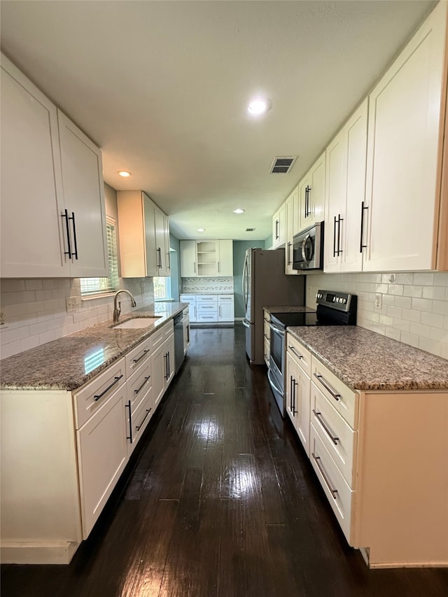 1502 Robin St, Mineola, TX 75773 - kitchen featuring stainless steel appliances, dark wood-style flooring, white cabinets, tasteful backsplash, and light stone countertops