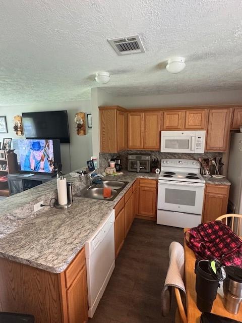 3940 Frontier Rd, Willis, TX 77378 - kitchen with white appliances, a peninsula, a textured ceiling, and dark wood-type flooring