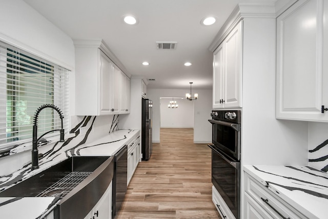 1805 E Ave, Katy, TX 77493 - kitchen featuring a chandelier, light wood-style floors, white cabinets, recessed lighting, and appliances with stainless steel finishes
