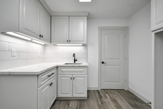 1805 E Ave, Katy, TX 77493 - kitchen with backsplash, light wood-style floors, white cabinets, and light stone counters