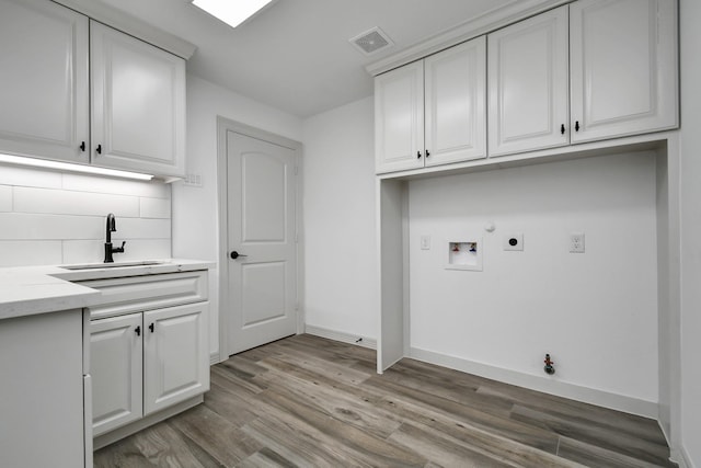 1805 E Ave, Katy, TX 77493 - washroom with hookup for a gas dryer, washer hookup, cabinet space, light wood-style floors, and electric dryer hookup