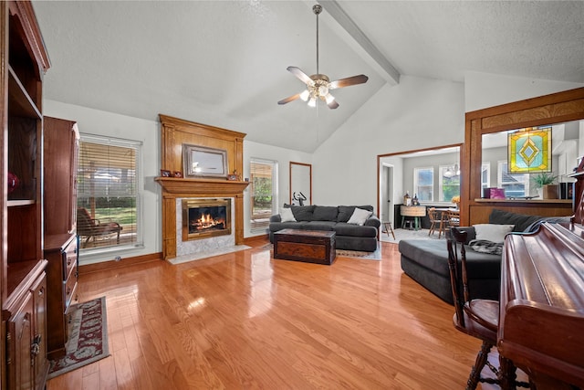 23011 Elephant Walk St, Spring, TX 77389 - living room featuring a fireplace, a ceiling fan, light wood-type flooring, beamed ceiling, and healthy amount of natural light