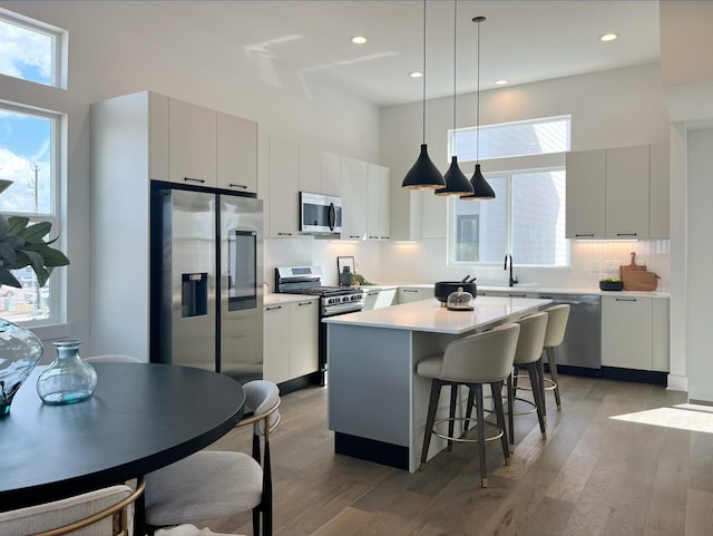 303F Marcella St, Houston, TX 77091 - kitchen featuring appliances with stainless steel finishes, modern cabinets, light wood finished floors, a kitchen bar, and a towering ceiling