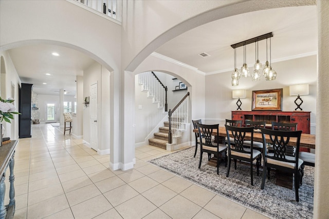 6903 Stevenson Dr, Missouri City, TX 77459 - dining space featuring light tile patterned floors, arched walkways, stairway, and ornamental molding