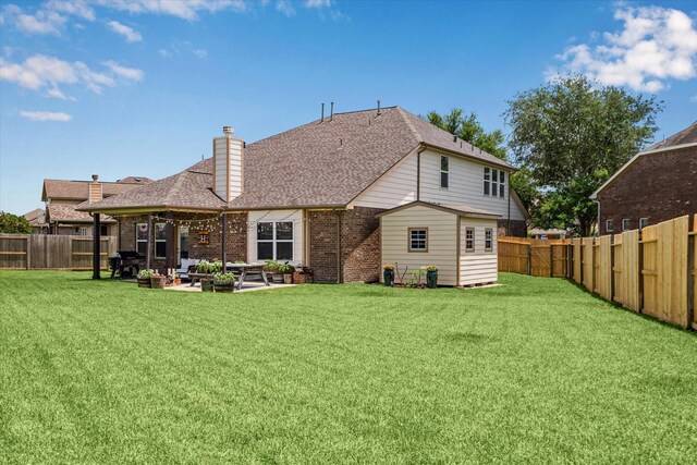6903 Stevenson Dr, Missouri City, TX 77459 - back of house featuring a fenced backyard, a patio, brick siding, a chimney, and a shingled roof