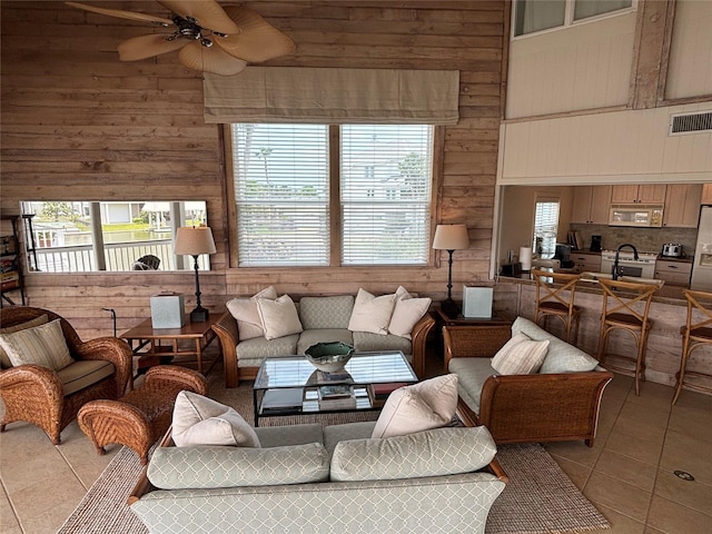 3514 Jolly Roger Cir, Galveston, TX 77554 - living area featuring light tile patterned floors, wood walls, ceiling fan, and a towering ceiling