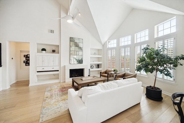 6403 Hidden Crest Way, Sugar Land, TX 77479 - living room featuring high vaulted ceiling, built in shelves, a fireplace, light wood-style floors, and a ceiling fan