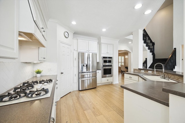6403 Hidden Crest Way, Sugar Land, TX 77479 - kitchen featuring appliances with stainless steel finishes, arched walkways, dark countertops, light wood-type flooring, and backsplash