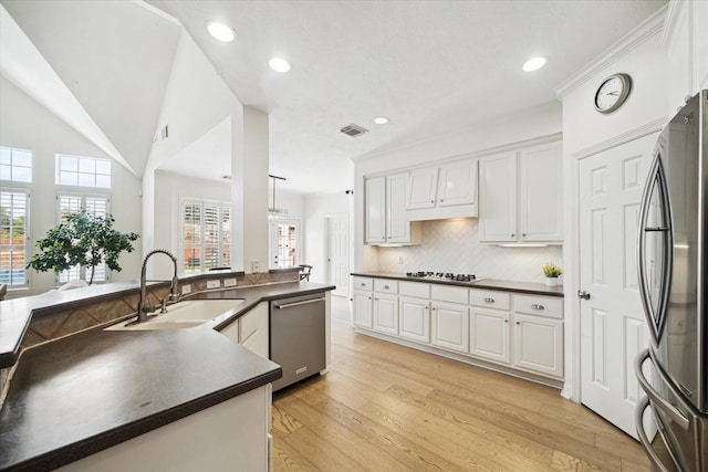 6403 Hidden Crest Way, Sugar Land, TX 77479 - kitchen with appliances with stainless steel finishes, dark countertops, white cabinetry, light wood-type flooring, and backsplash