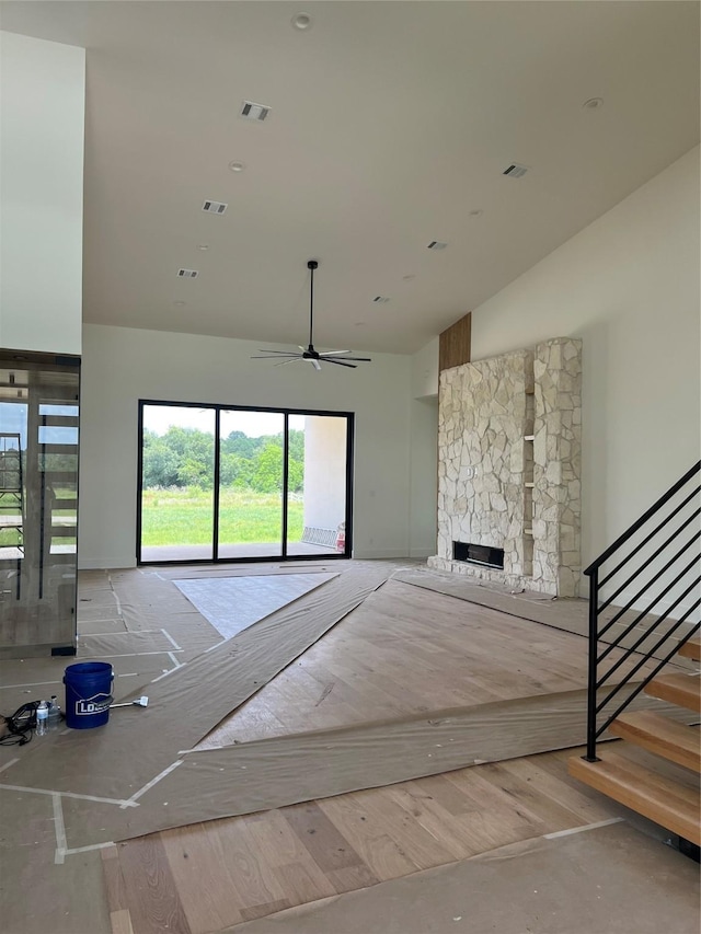 20410 Tealpointe Ridge Ln, Tomball, TX 77377 - unfurnished living room with plenty of natural light, stairs, a stone fireplace, ceiling fan, and high vaulted ceiling