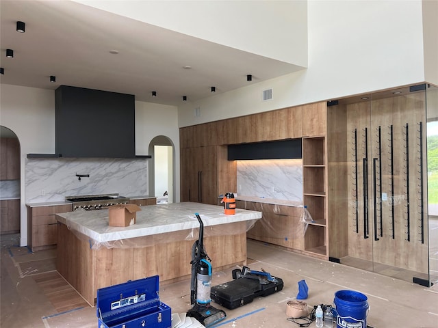 20410 Tealpointe Ridge Ln, Tomball, TX 77377 - kitchen featuring arched walkways, modern cabinets, brown cabinetry, extractor fan, and tasteful backsplash