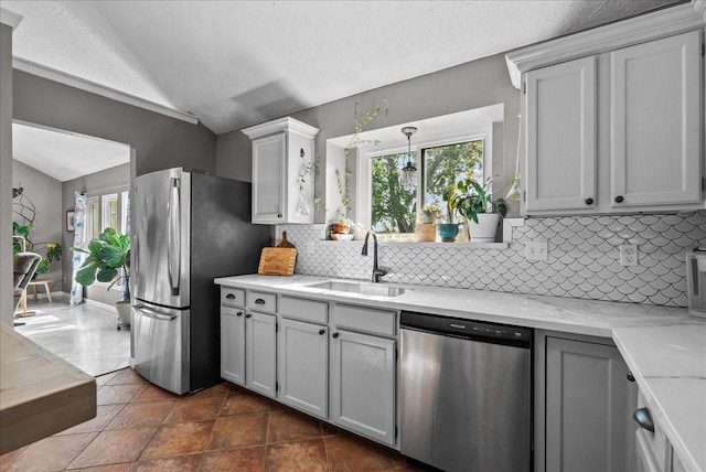 2004 Tuscarora Ct, League City, TX 77573 - kitchen featuring appliances with stainless steel finishes, lofted ceiling, tasteful backsplash, and light stone counters