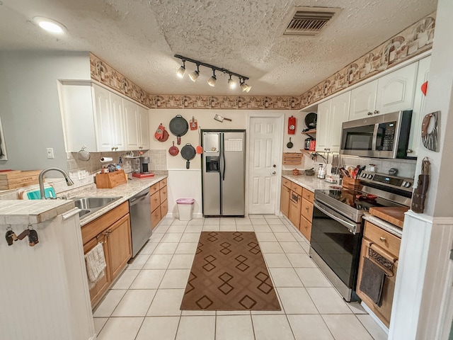309 Baycrest Dr, League City, TX 77573 - kitchen with appliances with stainless steel finishes, light countertops, white cabinetry, a textured ceiling, and light tile patterned floors