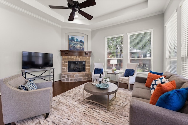 14 Painted Post Pl, The Woodlands, TX 77389 - living room featuring a tray ceiling, wood finished floors, a stone fireplace, ceiling fan, and ornamental molding