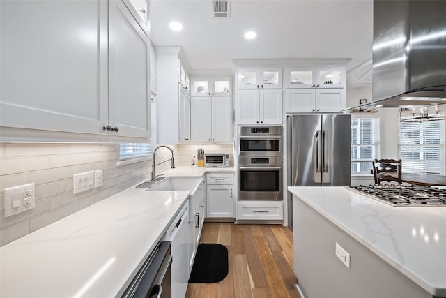 6602 Ranch Park Dr, Magnolia, TX 77354 - kitchen featuring appliances with stainless steel finishes, island range hood, decorative backsplash, light wood-style flooring, and recessed lighting