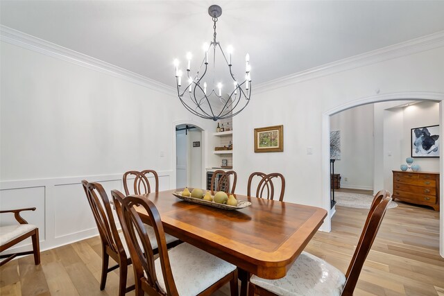 6602 Ranch Park Dr, Magnolia, TX 77354 - dining area with arched walkways, ornamental molding, a chandelier, light wood-type flooring, and a wainscoted wall