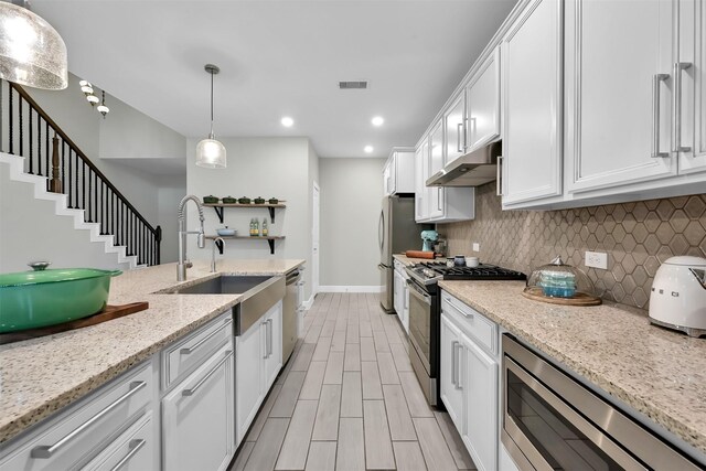 2411 Sunset Mist Ln, Conroe, TX 77304 - kitchen with appliances with stainless steel finishes, under cabinet range hood, white cabinets, tasteful backsplash, and recessed lighting