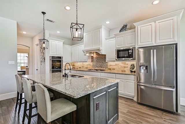 2424 Prairie Mist Ln, Friendswood, TX 77546 - kitchen featuring stainless steel appliances, arched walkways, decorative backsplash, white cabinets, and recessed lighting