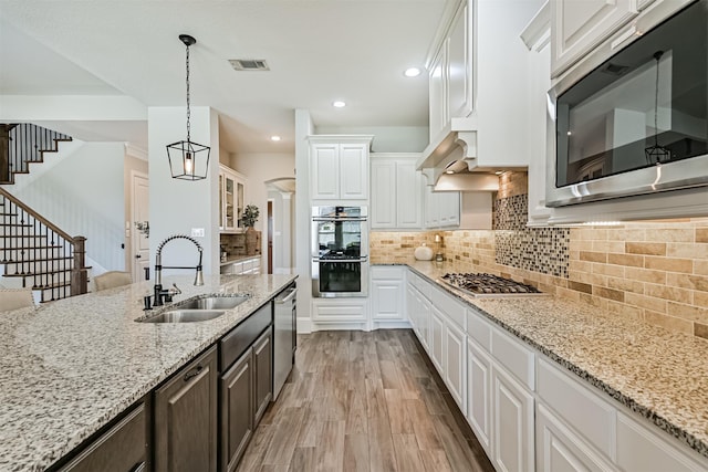 2424 Prairie Mist Ln, Friendswood, TX 77546 - kitchen with appliances with stainless steel finishes, white cabinetry, light wood finished floors, light stone counters, and decorative backsplash