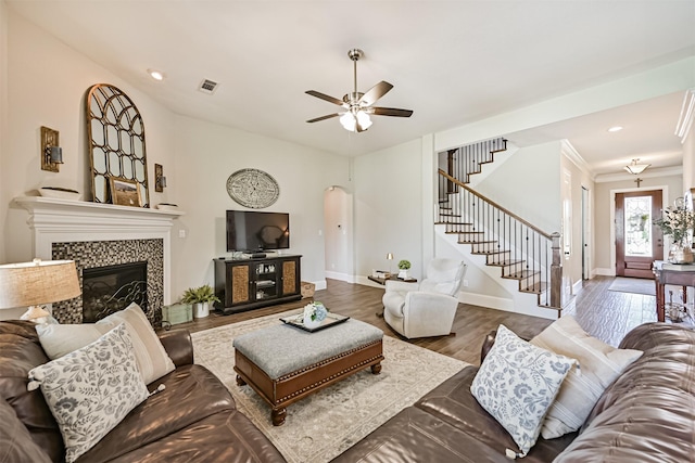 2424 Prairie Mist Ln, Friendswood, TX 77546 - living area with a tile fireplace, arched walkways, stairs, ceiling fan, and wood finished floors