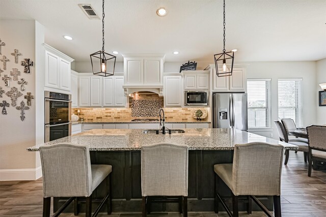 2424 Prairie Mist Ln, Friendswood, TX 77546 - kitchen with stainless steel appliances, backsplash, dark wood-style floors, white cabinets, and light stone countertops