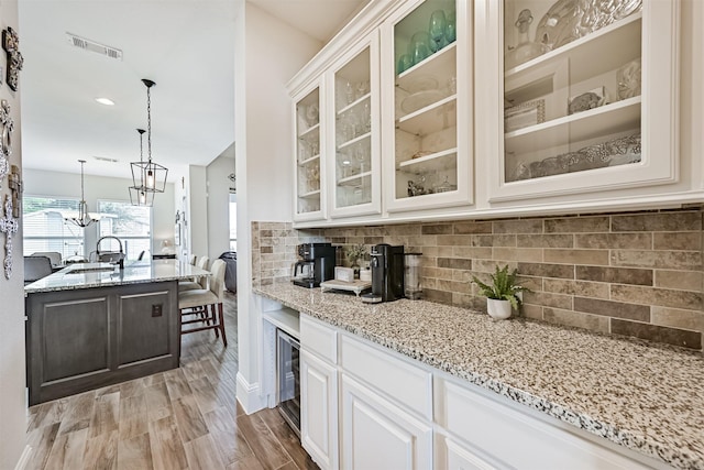 2424 Prairie Mist Ln, Friendswood, TX 77546 - kitchen featuring light stone counters, tasteful backsplash, beverage cooler, and glass insert cabinets