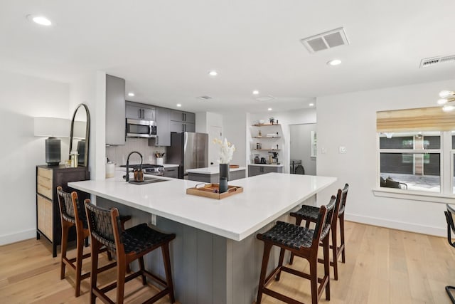 2327 Lamonte Ln, Houston, TX 77018 - kitchen with stainless steel appliances, gray cabinets, a peninsula, light countertops, and light wood-style floors