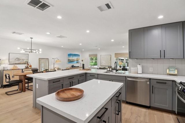 2327 Lamonte Ln, Houston, TX 77018 - kitchen featuring stainless steel dishwasher, gray cabinets, a peninsula, light wood-style floors, and tasteful backsplash