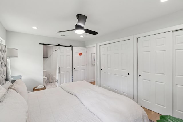 2327 Lamonte Ln, Houston, TX 77018 - bedroom featuring recessed lighting, multiple closets, a barn door, light wood-style floors, and ensuite bath
