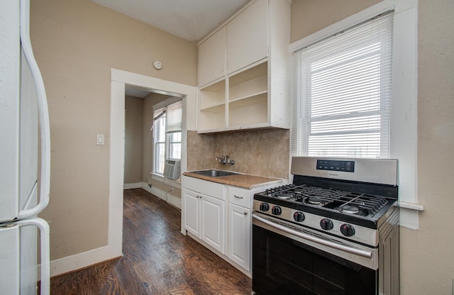 3412 Avenue S, Galveston, TX 77550 - kitchen featuring stainless steel range with gas stovetop, freestanding refrigerator, dark wood-type flooring, white cabinetry, and decorative backsplash
