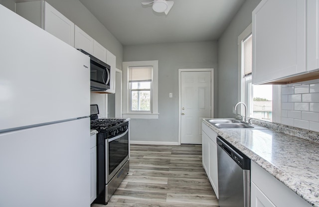 3412 Avenue S, Galveston, TX 77550 - kitchen with stainless steel appliances, white cabinets, light wood-style flooring, decorative backsplash, and light stone counters