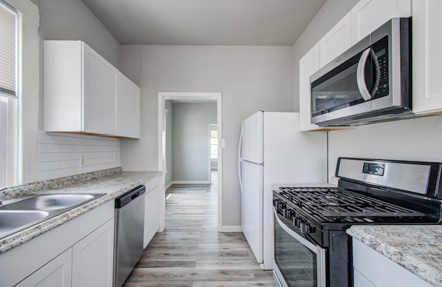 3412 Avenue S, Galveston, TX 77550 - kitchen with appliances with stainless steel finishes, light wood-style floors, white cabinets, and healthy amount of natural light