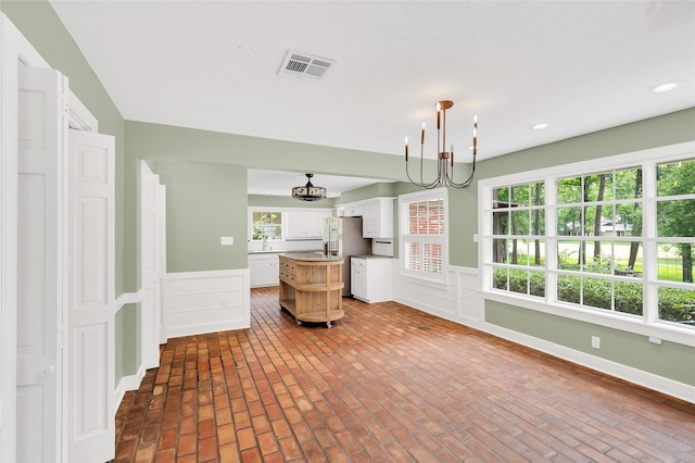 738 Stone Mountain Dr, Conroe, TX 77302 - kitchen with stainless steel fridge, white cabinetry, wainscoting, a chandelier, and a kitchen island