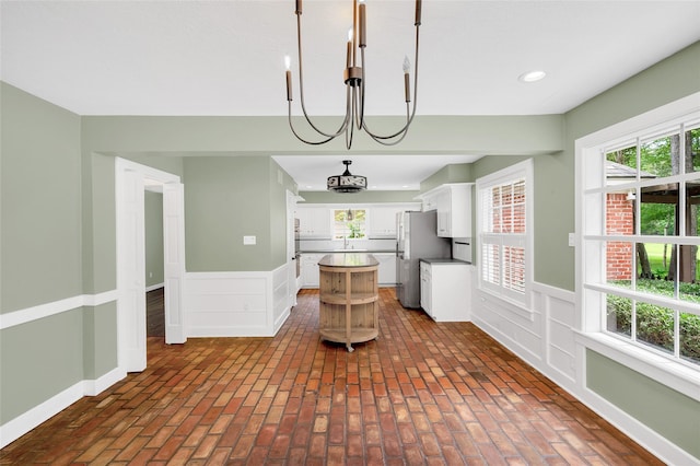 738 Stone Mountain Dr, Conroe, TX 77302 - kitchen featuring a wainscoted wall, white cabinets, freestanding refrigerator, a center island, and plenty of natural light