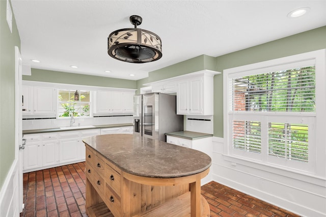 738 Stone Mountain Dr, Conroe, TX 77302 - kitchen with stainless steel fridge, brick floors, white cabinetry, a wainscoted wall, and recessed lighting