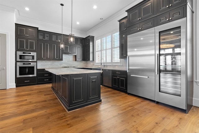 1156 Mosaico Ln, Houston, TX 77055 - kitchen featuring dark cabinetry, appliances with stainless steel finishes, ornamental molding, decorative backsplash, and pendant lighting