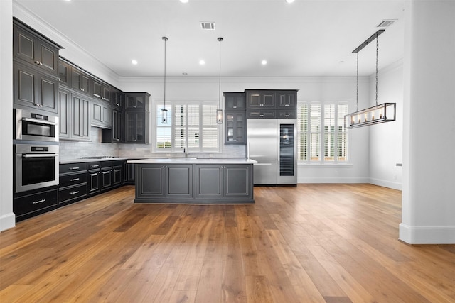 1156 Mosaico Ln, Houston, TX 77055 - kitchen with appliances with stainless steel finishes, light countertops, glass insert cabinets, a chandelier, and decorative backsplash